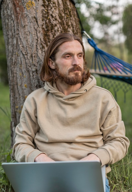 Front view of man in nature with laptop