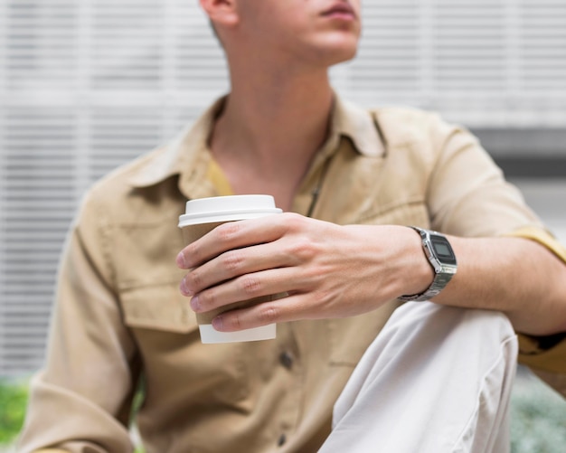 Free Photo front view of man outdoors holding cup of coffee