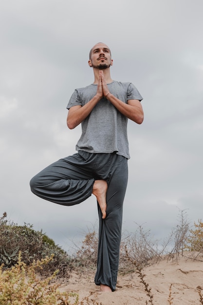 Free photo front view of man outside in yoga position