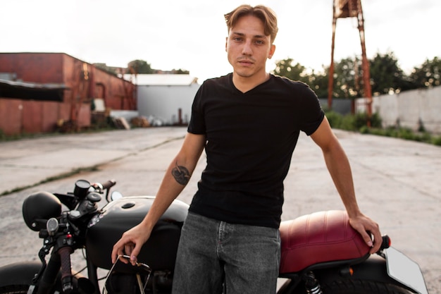 Front view man posing near motorcycle