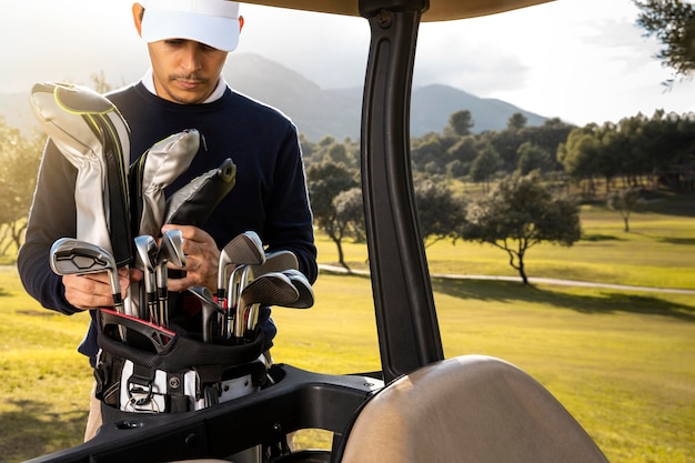 Free photo front view of man putting clubs in golf cart