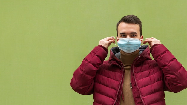 Free Photo front view of man putting on medical mask with copy space