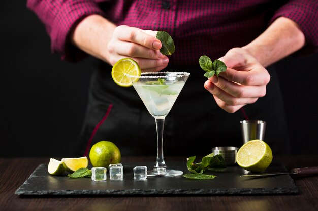 Front view of man putting mint on cocktail glass