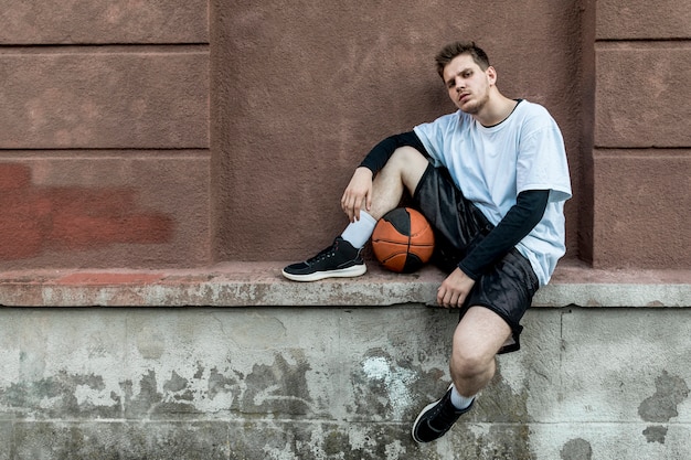 Front view man relaxing with a basketball