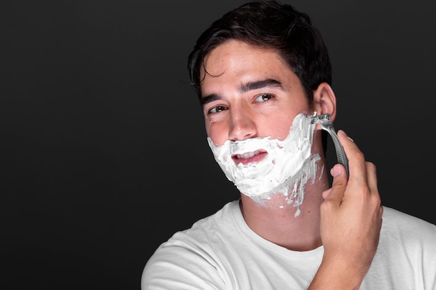 Front view man shaving beard