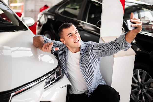 Free photo front view man taking a selfie with a car