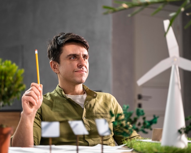 Front view of man thinking about an eco-friendly wind power project with wind turbines