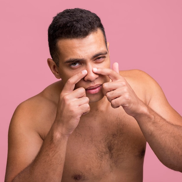 Front view of man trying to pop pimple on his nose