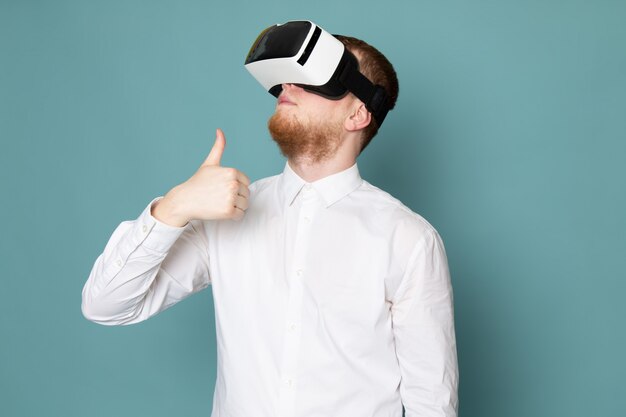 A front view man using vr in white t-shirt on the blue desk