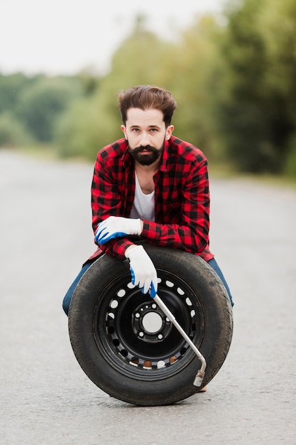 Free photo front view of man with tire and wrench