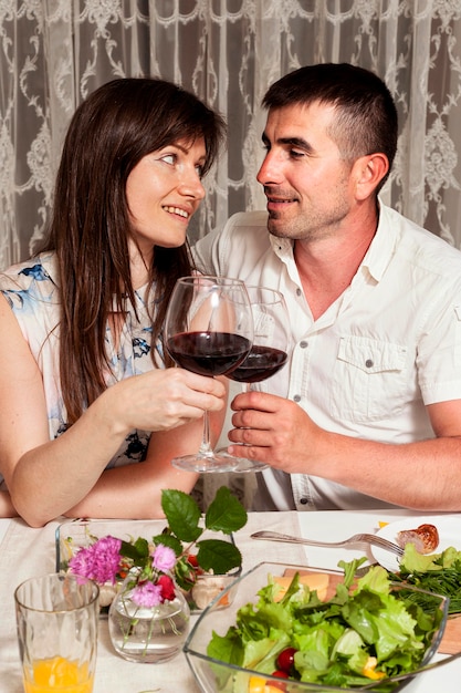 Front view of man and woman at dinner table with wine