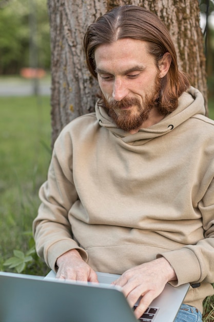 Front view of man working on laptop in nature