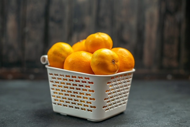 Front view mandarines and oranges in plastc basket on dark free space