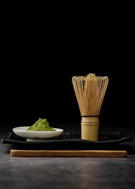 Free Photo front view of matcha tea powder with bamboo whisk