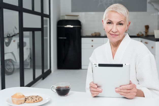 Front view of mature woman in bathrobe holding tablet