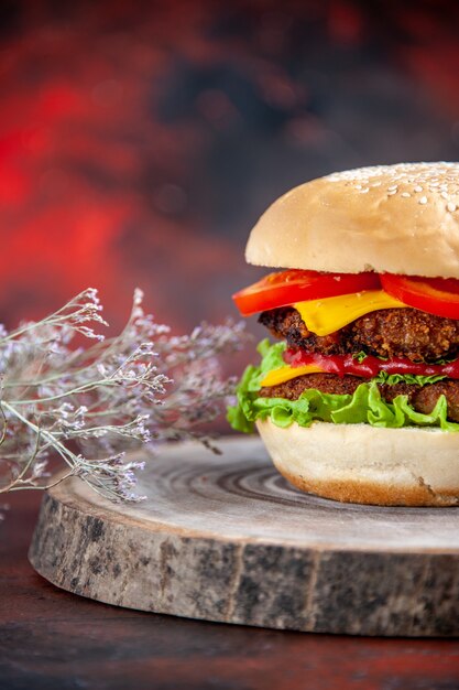 Front view meat burger with cheese tomatoes and salad on a dark background