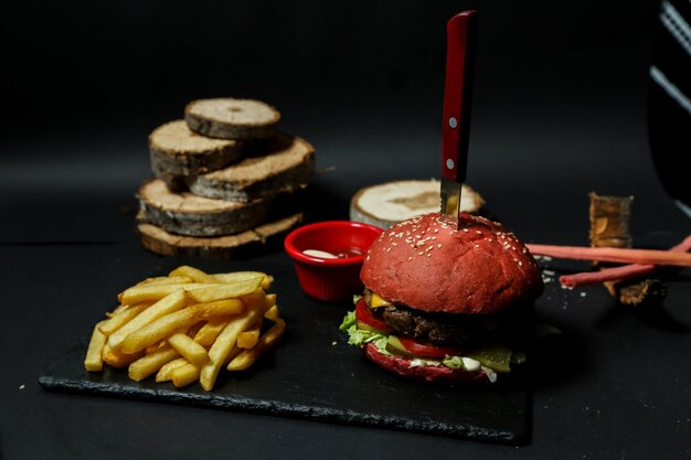 Front view meat burger with fries ketchup and mayonnaise on a stand with a knife