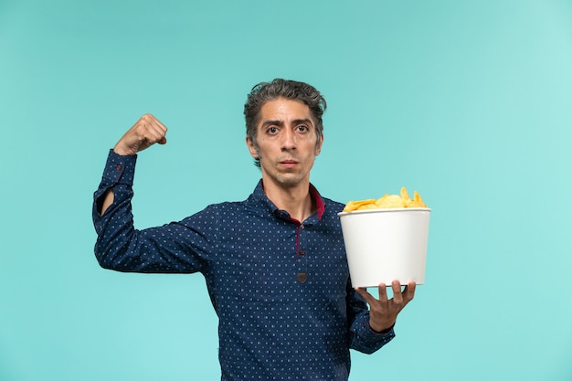 Free photo front view middle-aged male holding basket with cips on light-blue surface