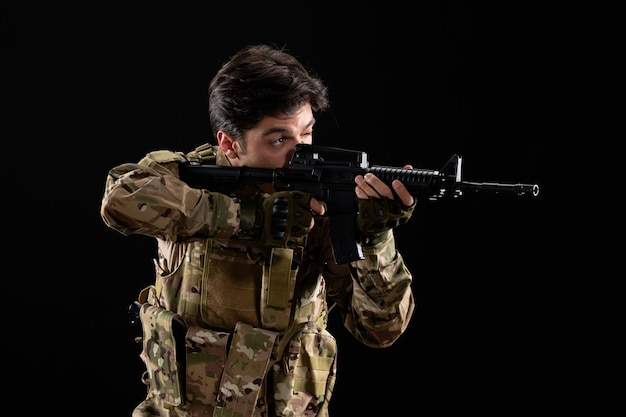 Free Photo front view military serviceman in uniform aiming rifle on black wall