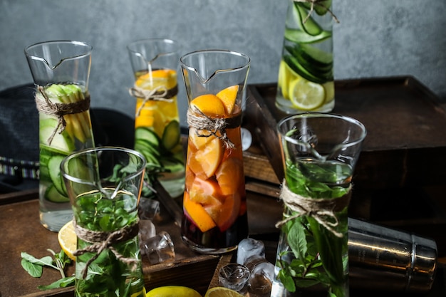 Front view mix detox water in a decanter with mint lemon apples and cucumbers