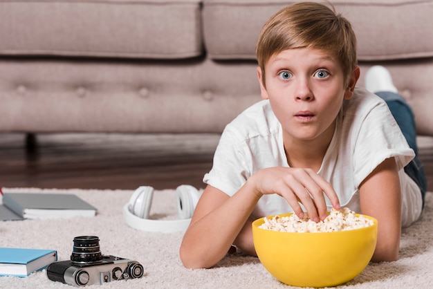 Front view of modern boy eating popcorn