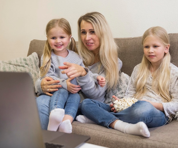 Free photo front view of mom and daughters with technology