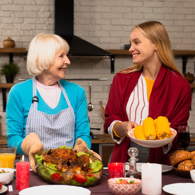 Free Photo front view of mother and daughter holding the food and looking at each other