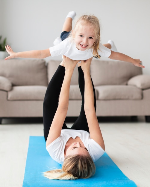 Front view of mother exercising with happy child at home