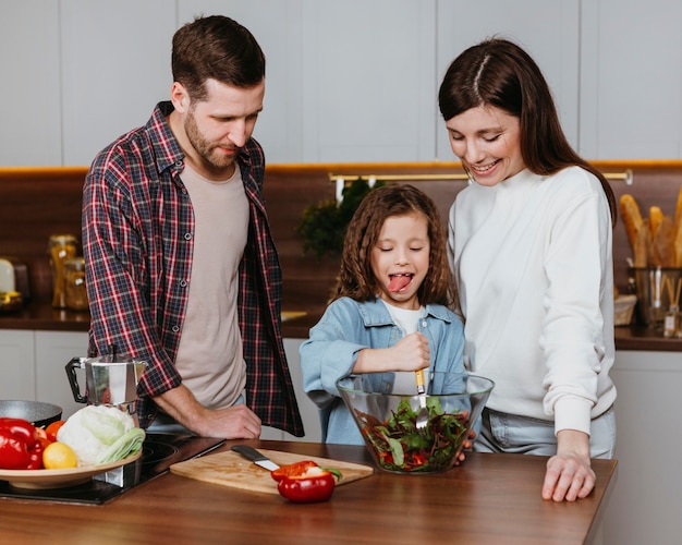 Front view of mother and father with child preparing food in the kitchen