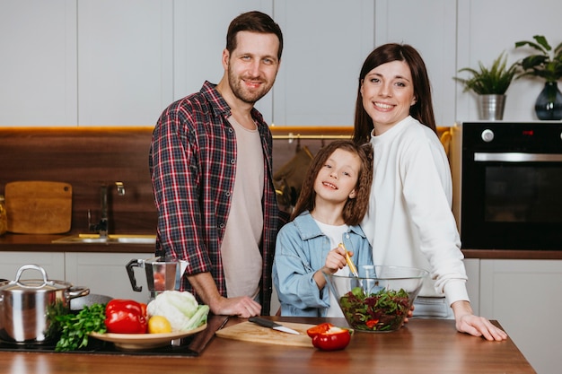 Front view of mother and father with daughter posing in the kitchen