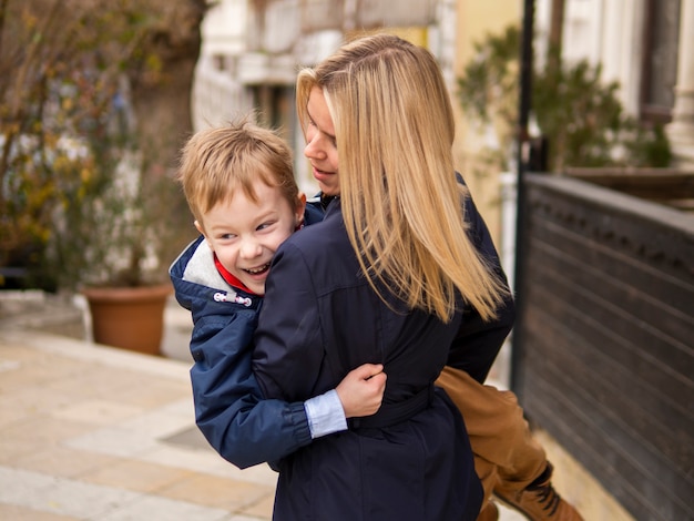 Free photo front view mother holding young boy outdoors