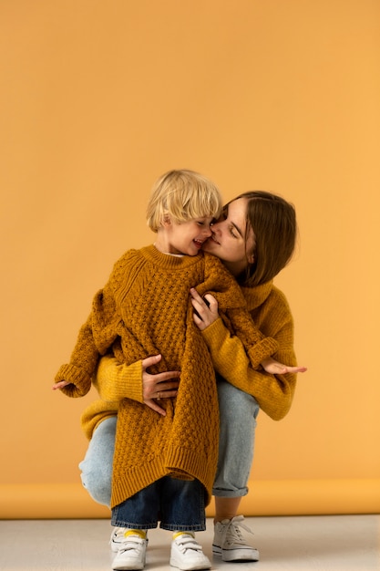 Front view mother kissing kid on cheek