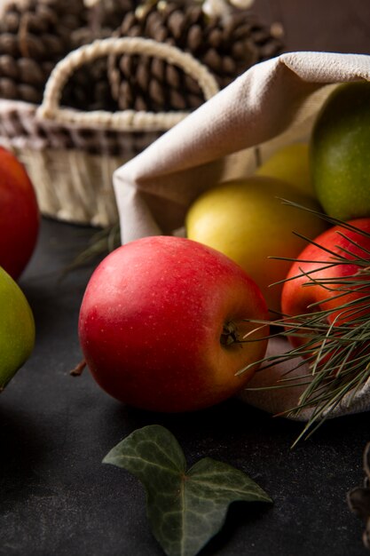 Front view multi-colored apples in a burlap bag on a black table