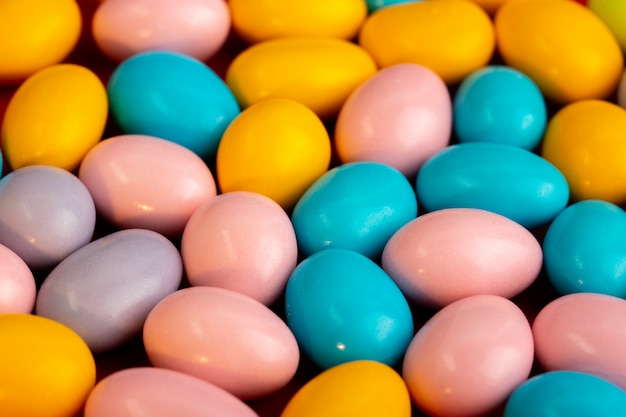 A front view multicolored candies bon-bons sweet tasty on the red tissue dark background confectionery sweetness biscuits