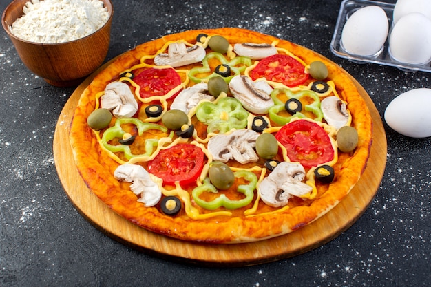 Free photo front view mushroom pizza with red tomatoes bell-peppers olives and mushrooms all sliced inside with eggs and flour on grey