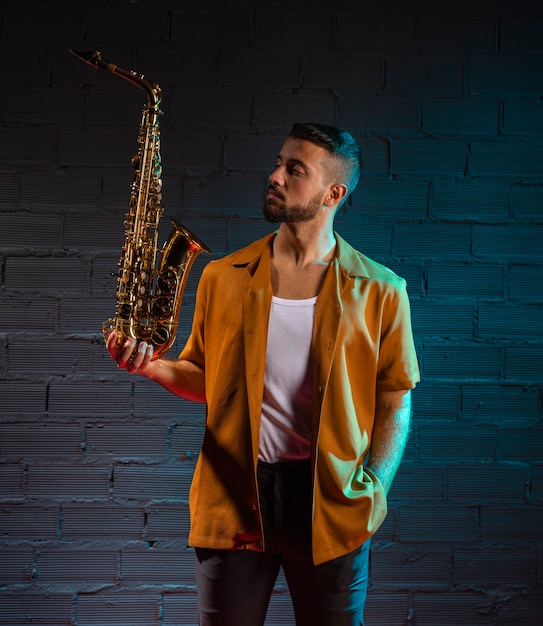 Free photo front view of musician holding a saxophone