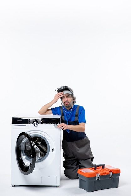 Free photo front view of musing repairman sitting near washer tools bag on white wall