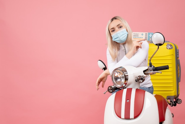 Free photo front view nice young lady on moped with yellow suitcase holding plane ticket