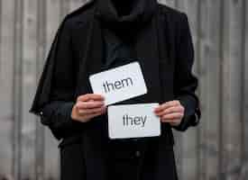 Free photo front view non binary person holding pronouns cards