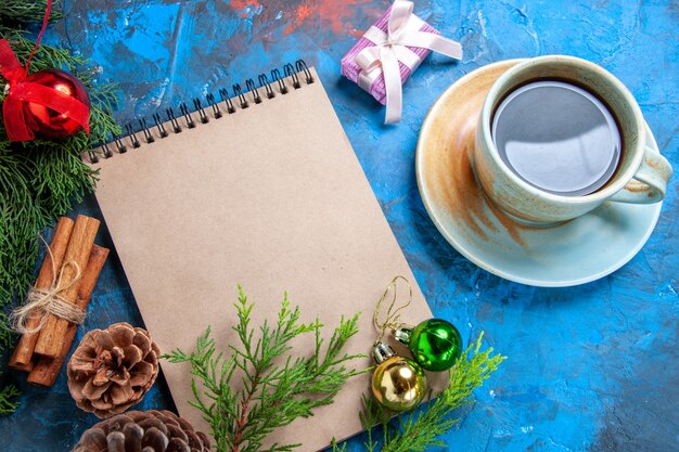 Front view a notebook pine tree branches pinecone a cup of tea on blue background