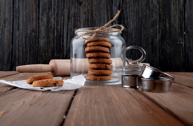 Front view oatmeal cookies in a jar with a rolling pin on the table