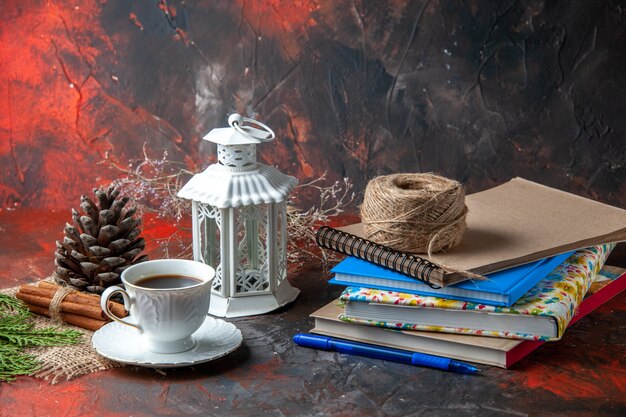 Front view of office suppliances and pen cinnamon limes conifer cone and a cup of tea a ball of rope on dark background