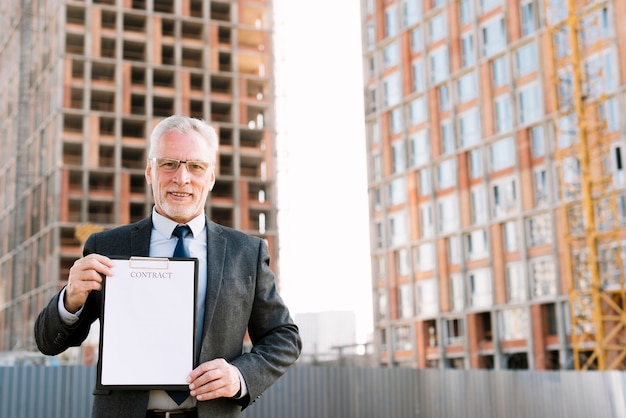 Front view old man in suit holding contract