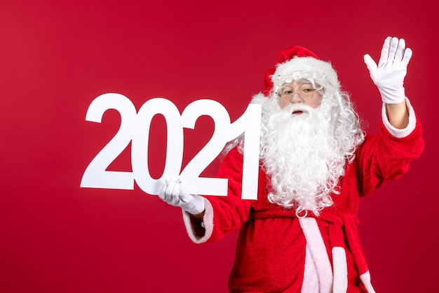 Front view of old santa claus holding writing on red wall