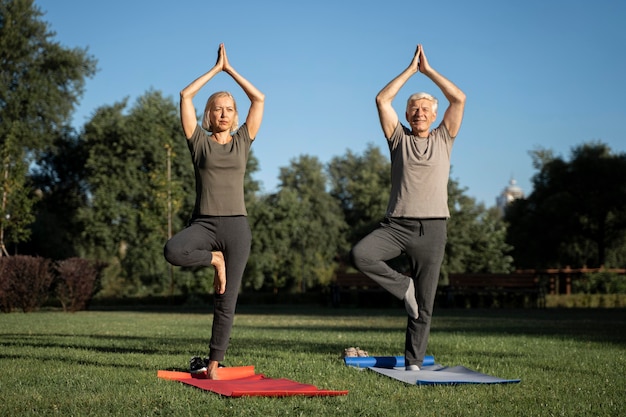 Free photo front view of older couple doing yoga outdoors