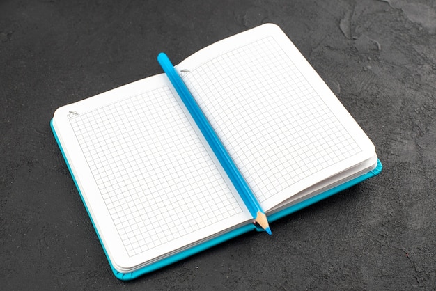 Front view of open blue notebook and pen on black