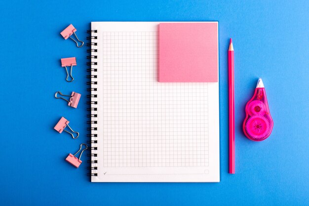 Front view open copybook with pink sticker on the blue desk