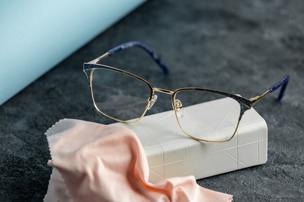 A front view optical sunglasses on the grey desk along with cream cleaning tissue isolated sight vision eyes