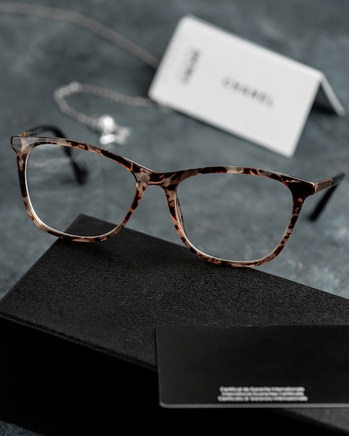 A front view optical sunglasses on the grey desk with silver bracelets isolated sight vision eyes