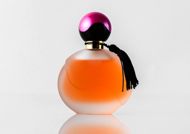 Free Photo a front view orange designed perfume with black and purple cap isolated on the white floor